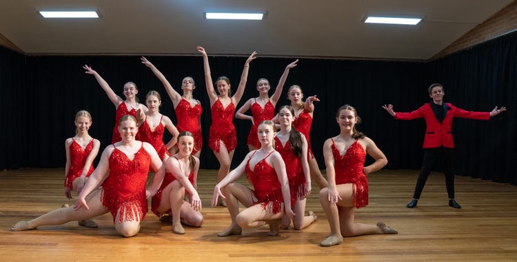 A group of female students and one male student in red costumes posing for a photo