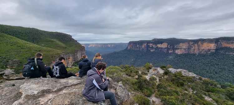 A group of people sitting on a rock overlooking a valley