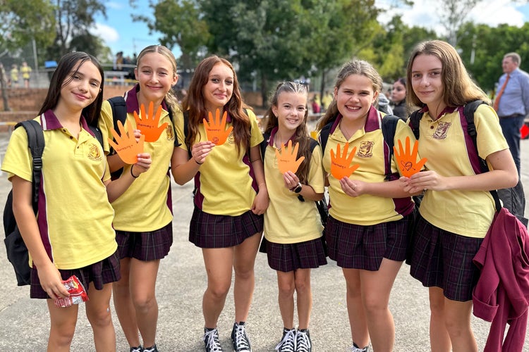 A group of girls wearing school uniform holding orange hands