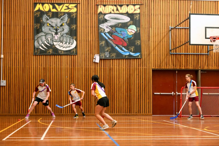 Four students playing indoor hockey in school hall