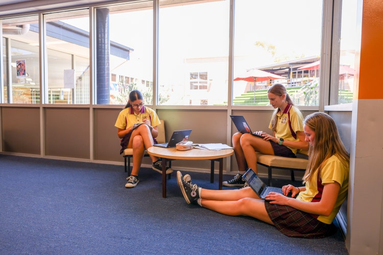 A group of girls sitting on the floor with laptops