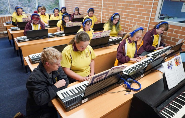 A group of people in a classroom learning the piano keyboard
