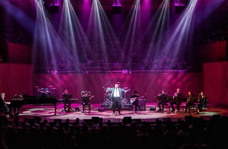 A person performing on stage with a band