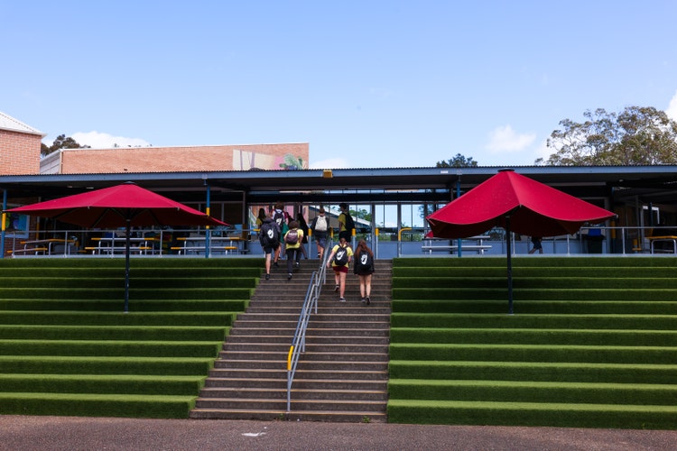 A group of people walking up stairs with red umbrellas