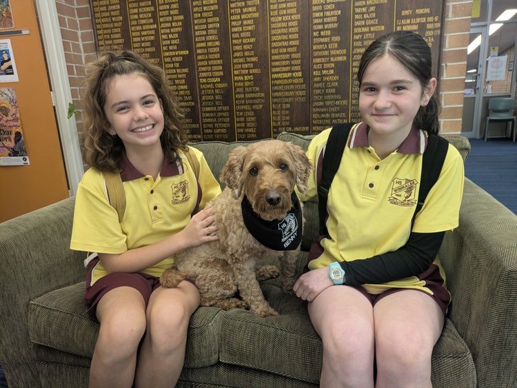 Two girls sitting on a couch with a dog